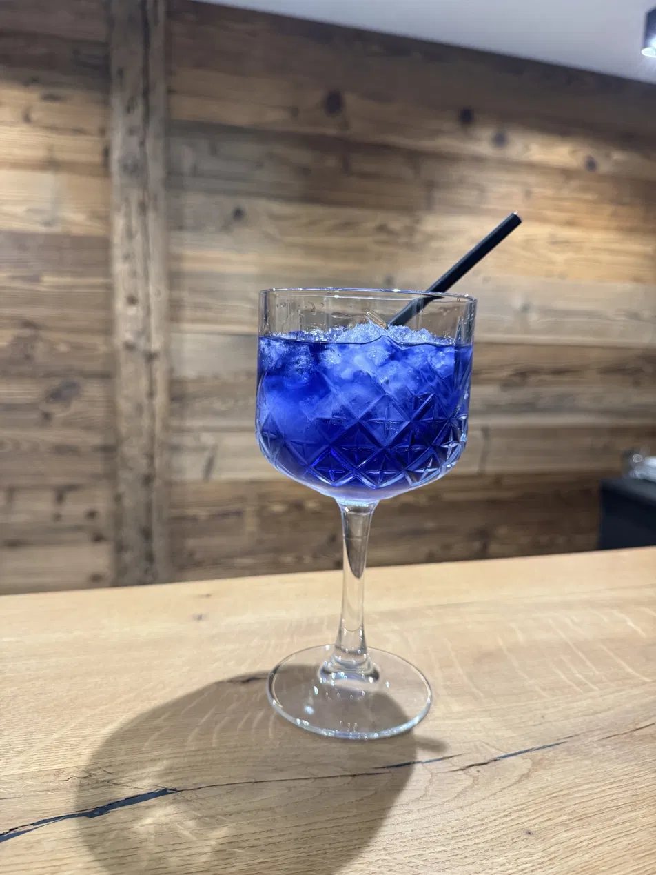 Blauer Drink auf Crushed Ice an der Bar aus Altholz