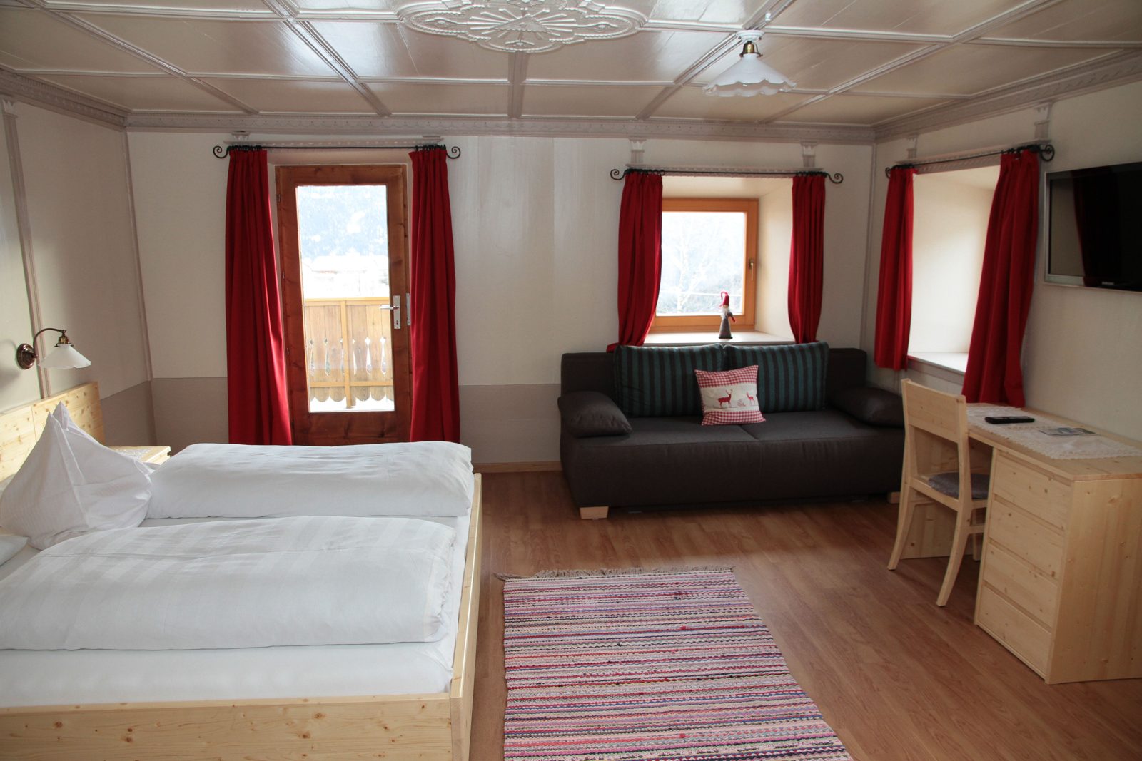 Panoramazimmer mit Stubendecke, Massivholzmöbeln, Schlafcouch und Balkon mit Bergblick